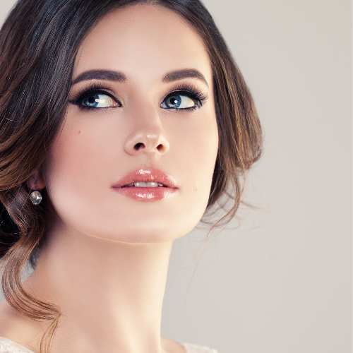 Mujer vestida de novia con ojos azules, labios carnosos de color rosa, pelo con un recogido, maquillaje diseñado para resaltar la belleza un día tan especial realizado en Madrid en el estudio de belleza Ernesto Caballero Beauty Studio